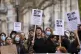 Protesters show placards as Chancellor Rachel Reeves is abou