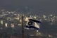 An Israeli flag flutters in front of the village of Majdal S