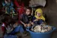 Children sit in front of moldy bread in their shelter, in As