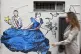 A woman walks past a wall sticker by French artist Combo dep