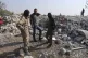 People look at a destroyed house near the village of Barisha