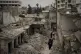 Women walk in a neighbourhood heavily damaged by airstrikes 