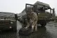 A soldier stows his rucksack in a truck that will leave the 