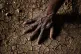 A man places his hand on the parched soil in the Greater Upp