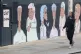 A woman passes a mural showing BAME medical, transport and c