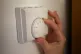 A person using a central heating thermostat