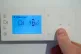 A homeowner turns down the temperature of a central heating 