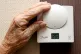 An elderly lady adjusting her thermostat