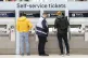 A member of staff assists a person at the ticket machines in