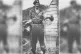 A British Soldier holds up the heads of two Malaysians